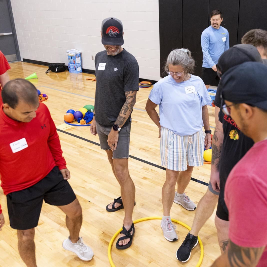  Staff practice a gym game with a hula hoop